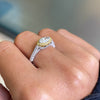 A marquise diamond engagement ring with an east west setting  halo of round yellow diamonds set in rose gold, with smaller white round brilliant cut diamonds set in a contrasting band of platinum. side view