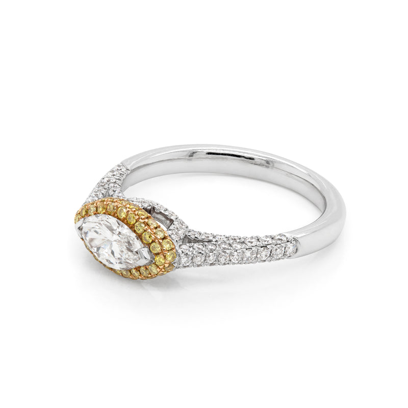 A marquise diamond engagement ring with an east west setting  halo of round yellow diamonds set in rose gold, with smaller white round brilliant cut diamonds set in a contrasting band of platinum. side view