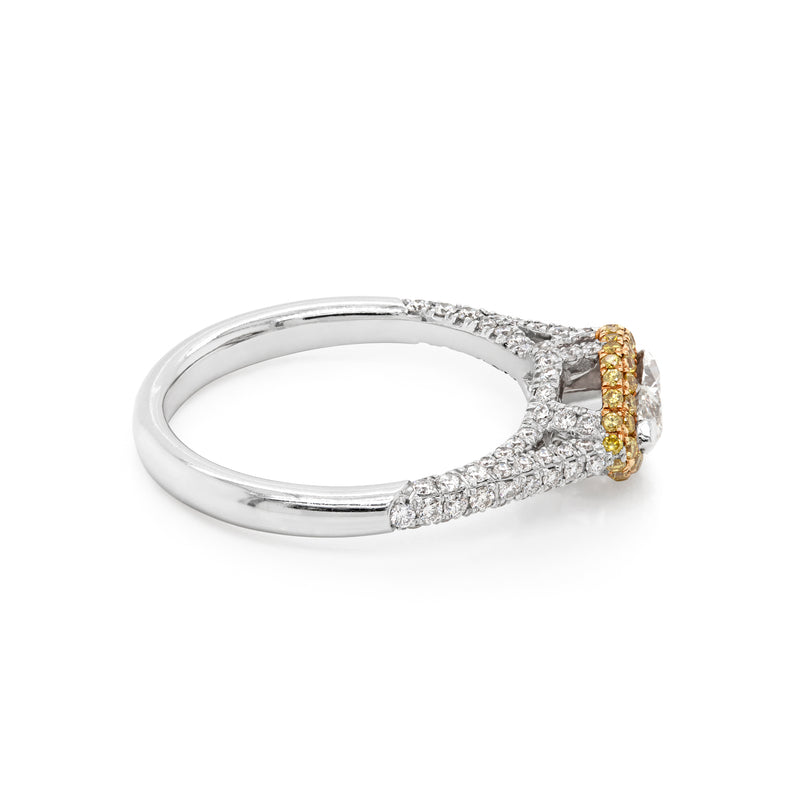 A marquise diamond engagement ring with a halo of round yellow diamonds set in rose gold, with smaller white round brilliant cut diamonds set in a contrasting band of platinum. side view
