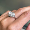 An Art Deco style engagement ring with a central old cut diamond and additional diamonds set in a platinum mount with open work detailing on hand
