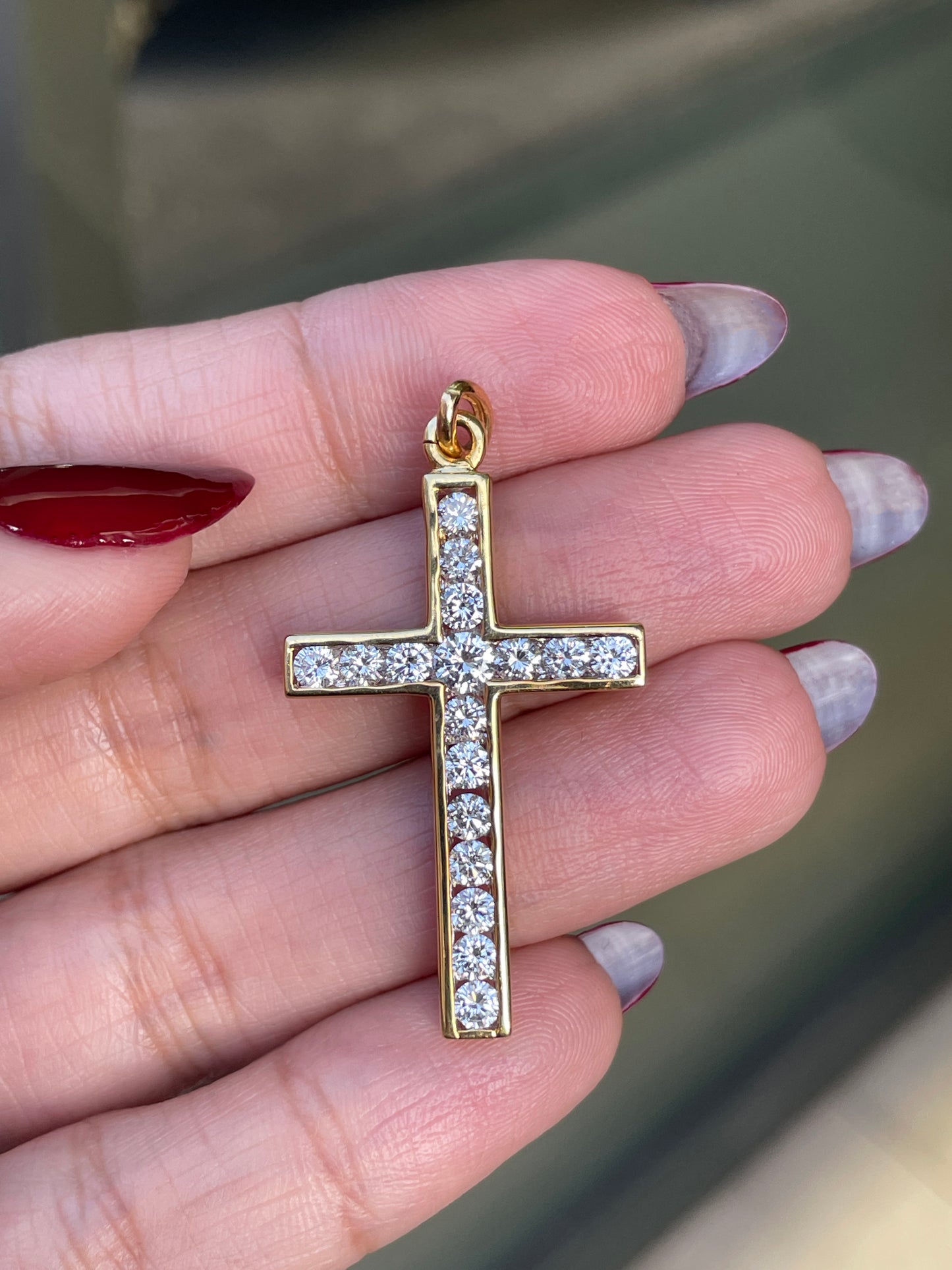 An 18 carat yellow gold diamond cross pendant with multiple round brilliant cut diamonds set within it.