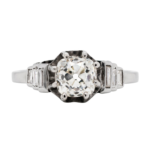 Antique engagement ring with a central old cut diamond, surrounded by step baguette diamond shoulders and smaller baguette cuts.