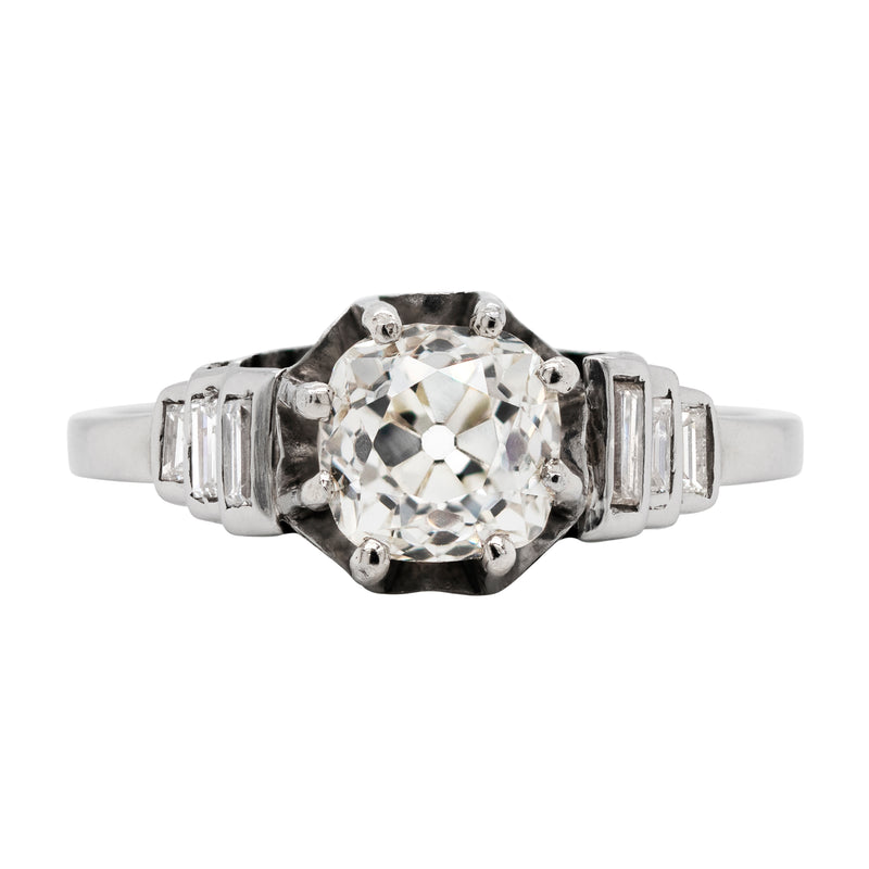 Antique engagement ring with a central old cut diamond, surrounded by step baguette diamond shoulders and smaller baguette cuts.