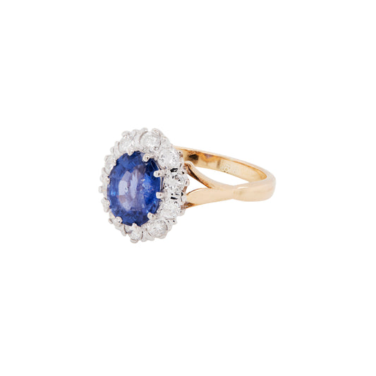 Gold ring with a blue gemstone and diamond accents on a white background