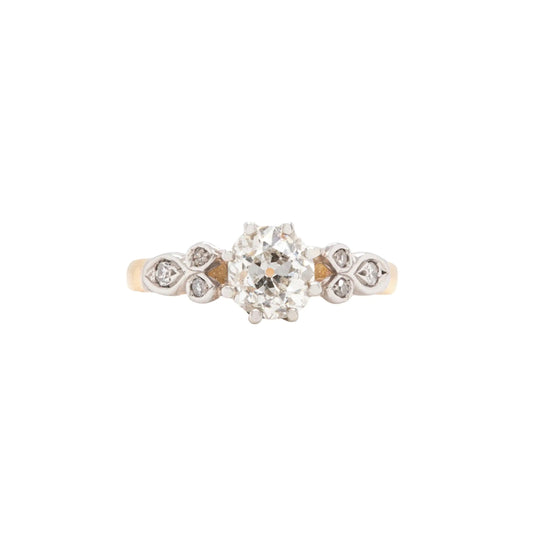 An 18K white gold and platinum engagement ring with a central old mine cut diamond and surrounding smaller diamonds.