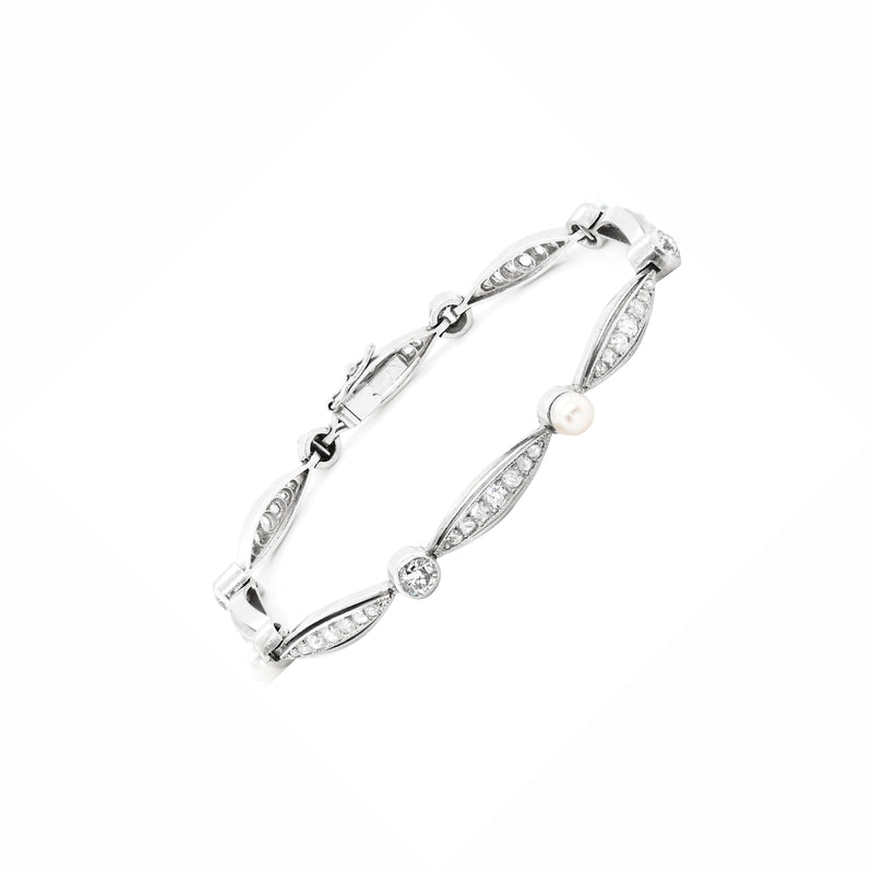 A vintage French pearl and diamond platinum bracelet with a series of alternating old cut diamonds and natural pearls, featuring a rub-over setting.