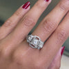 An Art Deco style engagement ring with a central old cut diamond and additional diamonds set in a platinum mount with open work detailing on hand