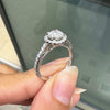 0.70ct E VS1 diamond halo cluster engagement ring in platinum with round brilliant cut centre stone, halo and diamond shoulders on hand