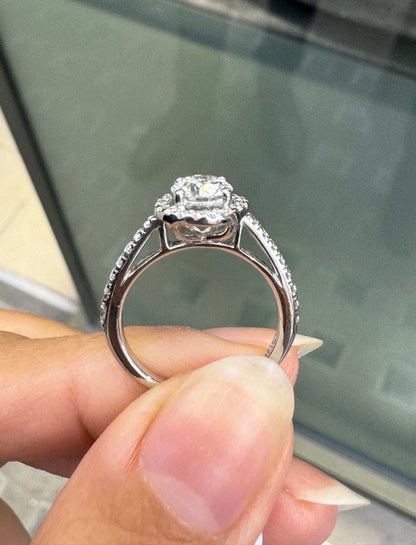 0.70ct E VS1 diamond halo cluster engagement ring in platinum with round brilliant cut centre stone, halo and diamond shoulders on hand