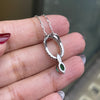 An 18 carat white gold oval pendant featuring a central emerald, surrounded by round brilliant cut diamonds set in a claw-like design.