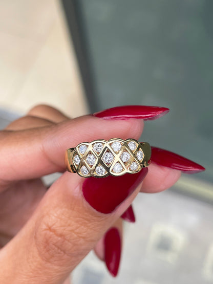 An 18 carat yellow gold lattice band ring with round brilliant cut diamond being held between fingers