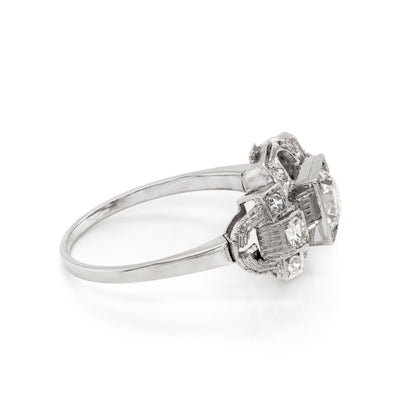 An Art Deco style engagement ring with a central old cut diamond and additional diamonds set in a platinum mount with open work detailing 