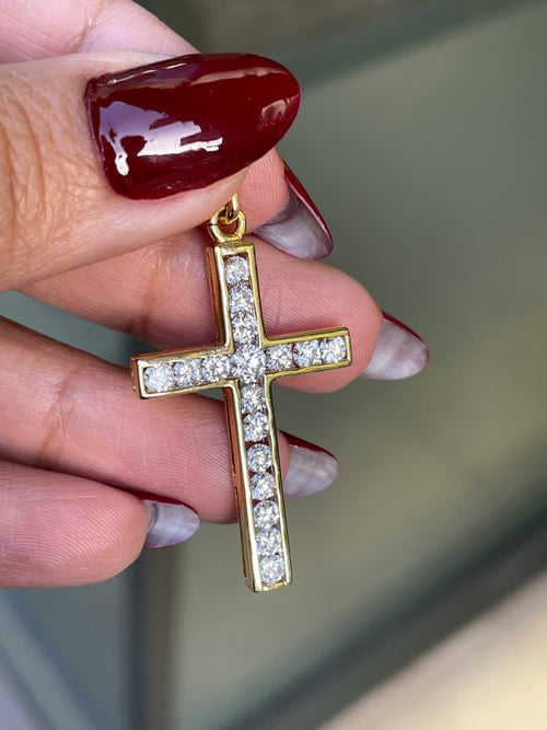 An 18 carat yellow gold diamond cross pendant with multiple round brilliant cut diamonds set within it.