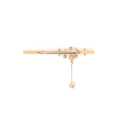 An 18 carat yellow gold bar brooch with five round brilliant cut diamonds attached to it, displayed against a white background.