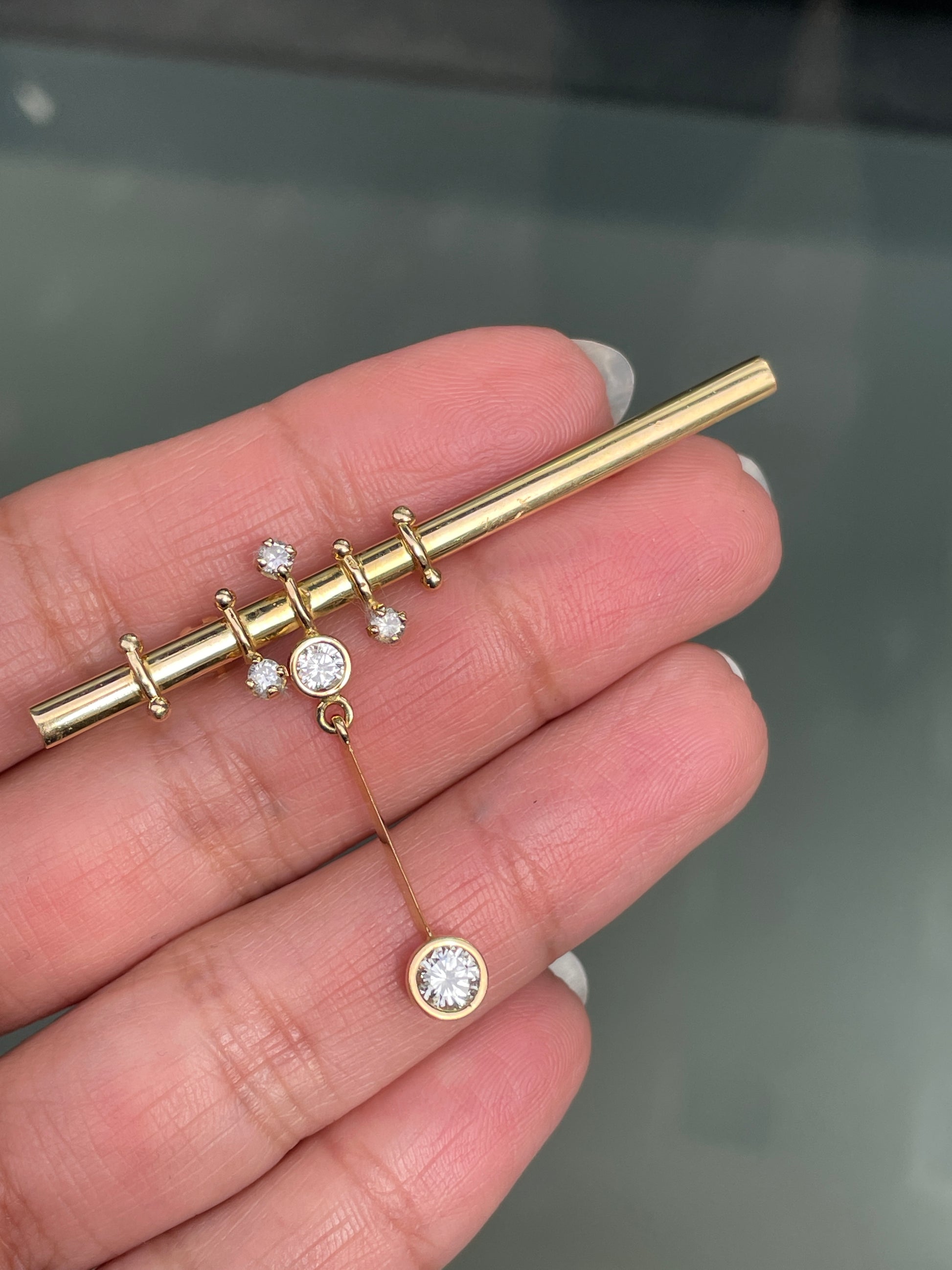 An 18 carat yellow gold bar brooch with five round brilliant cut diamonds attached to it