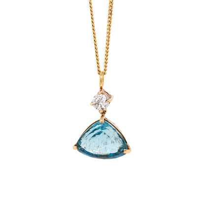 An aquamarine and diamond necklace with a gold bale, featuring a large aquamarine pendant and a smaller diamond, set in gold claws.