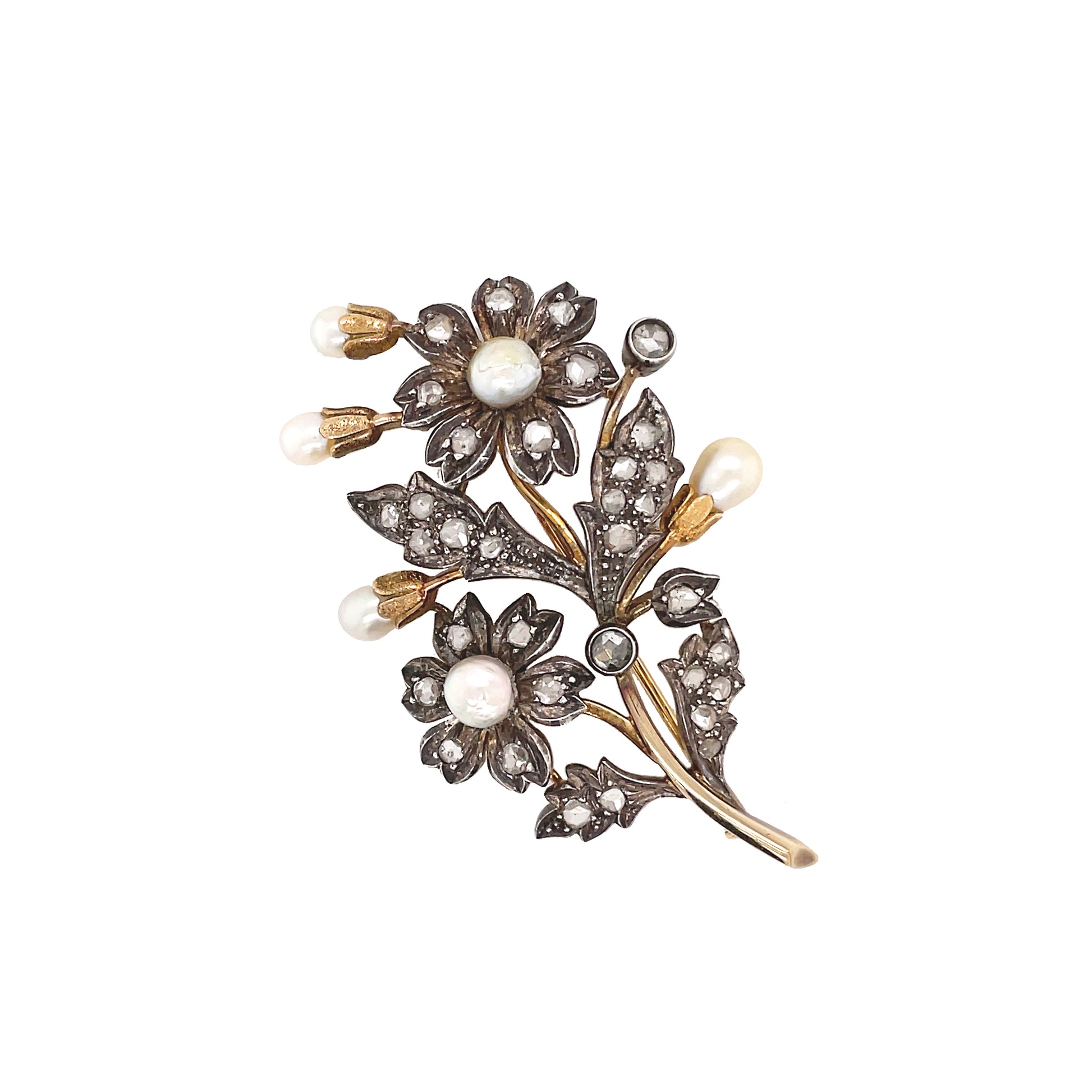 An antique floral brooch with pearl accents and rose cut diamonds, predominantly silver in color with a gold base, from the late 1800s.