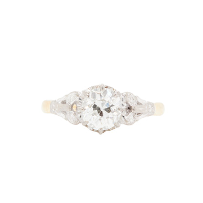 An antique Edwardian engagement ring featuring a 1.29ct old mine cut diamond in an elevated eight claw platinum setting with Art Deco motifs on the shoulders, complemented by a high polish 18 carat yellow gold band.