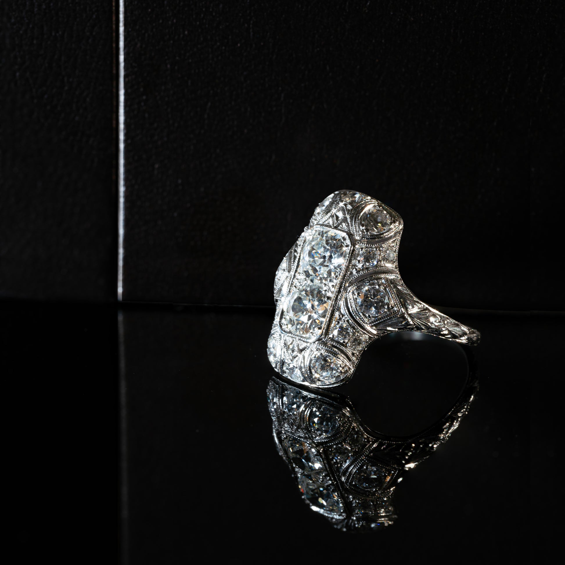 An antique Art Deco old mine cut diamond vertical platinum dress ring with smaller old European cut diamonds set in a rectangular panel with milgrain detailing.