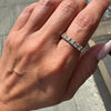 Hand wearing a diamond ring on a blurred outdoor background