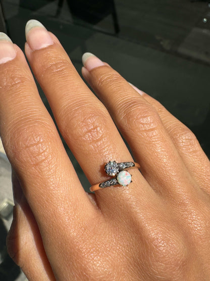 Hand wearing a ring with an opal stone on a blurred background