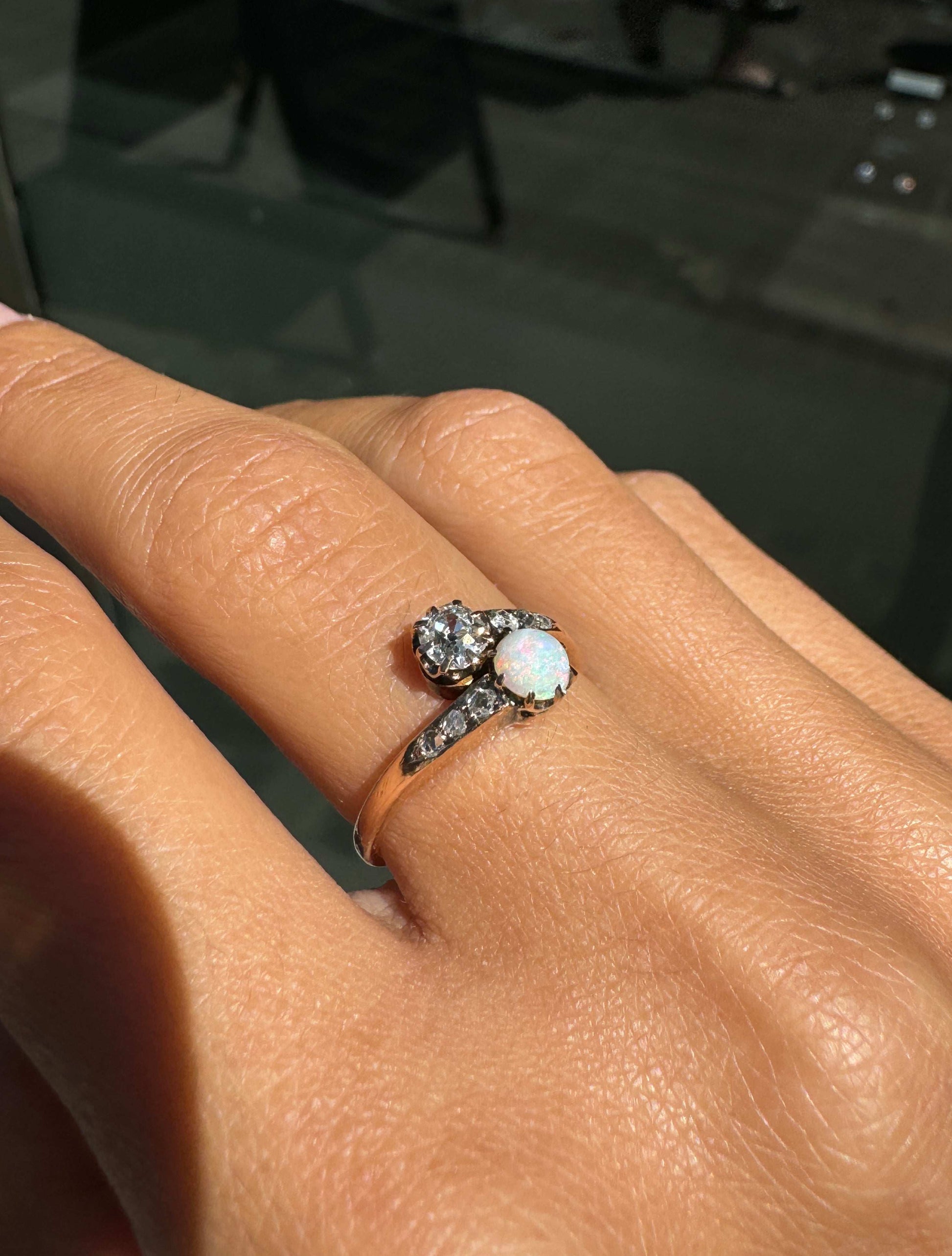 Close-up of a hand wearing an ornate ring with a central gemstone on a blurred background