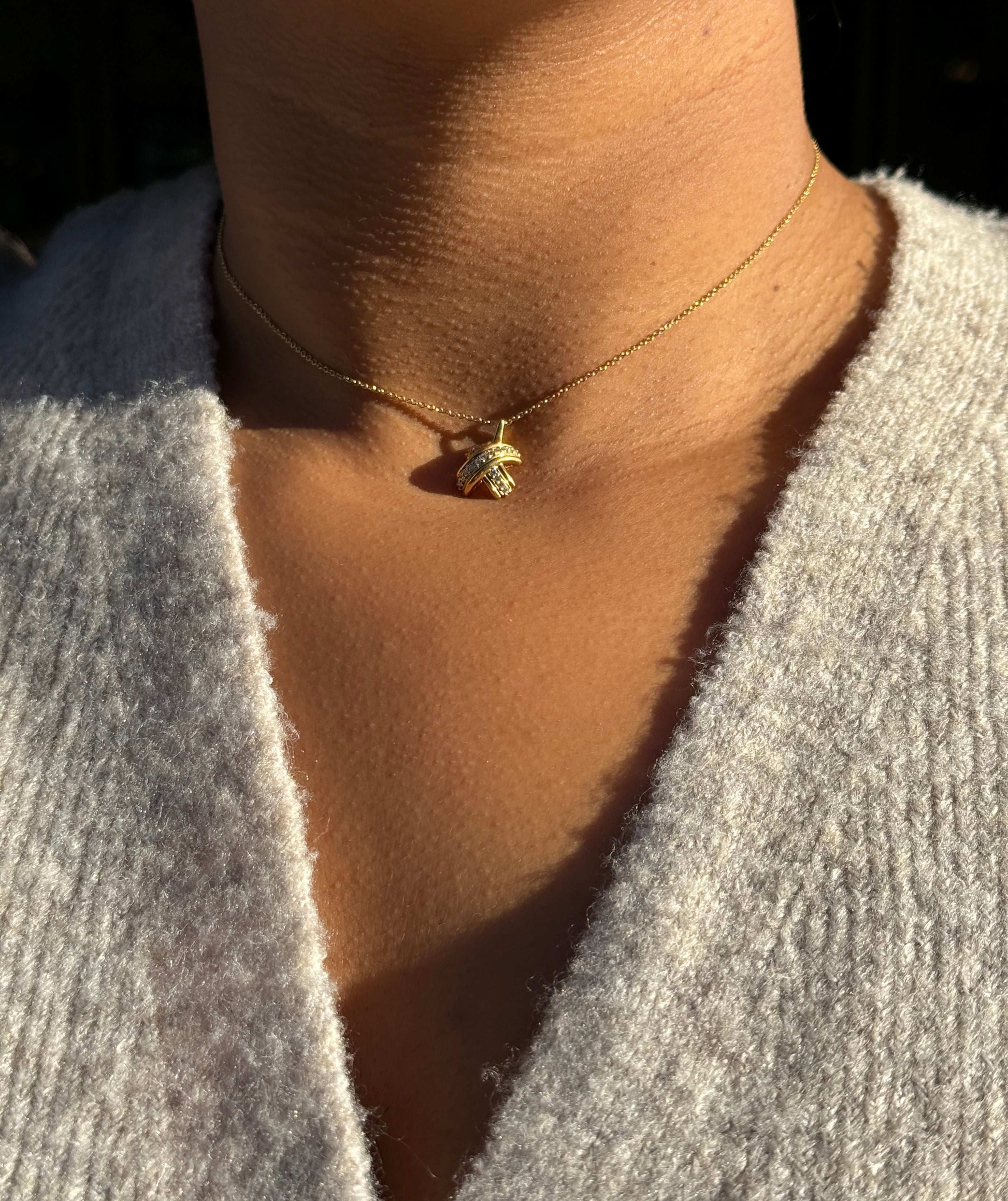 lady wearing Tiffany & Co. Signature X Diamond & 18 Carat Yellow Gold 'Kiss' Pendant Necklace 