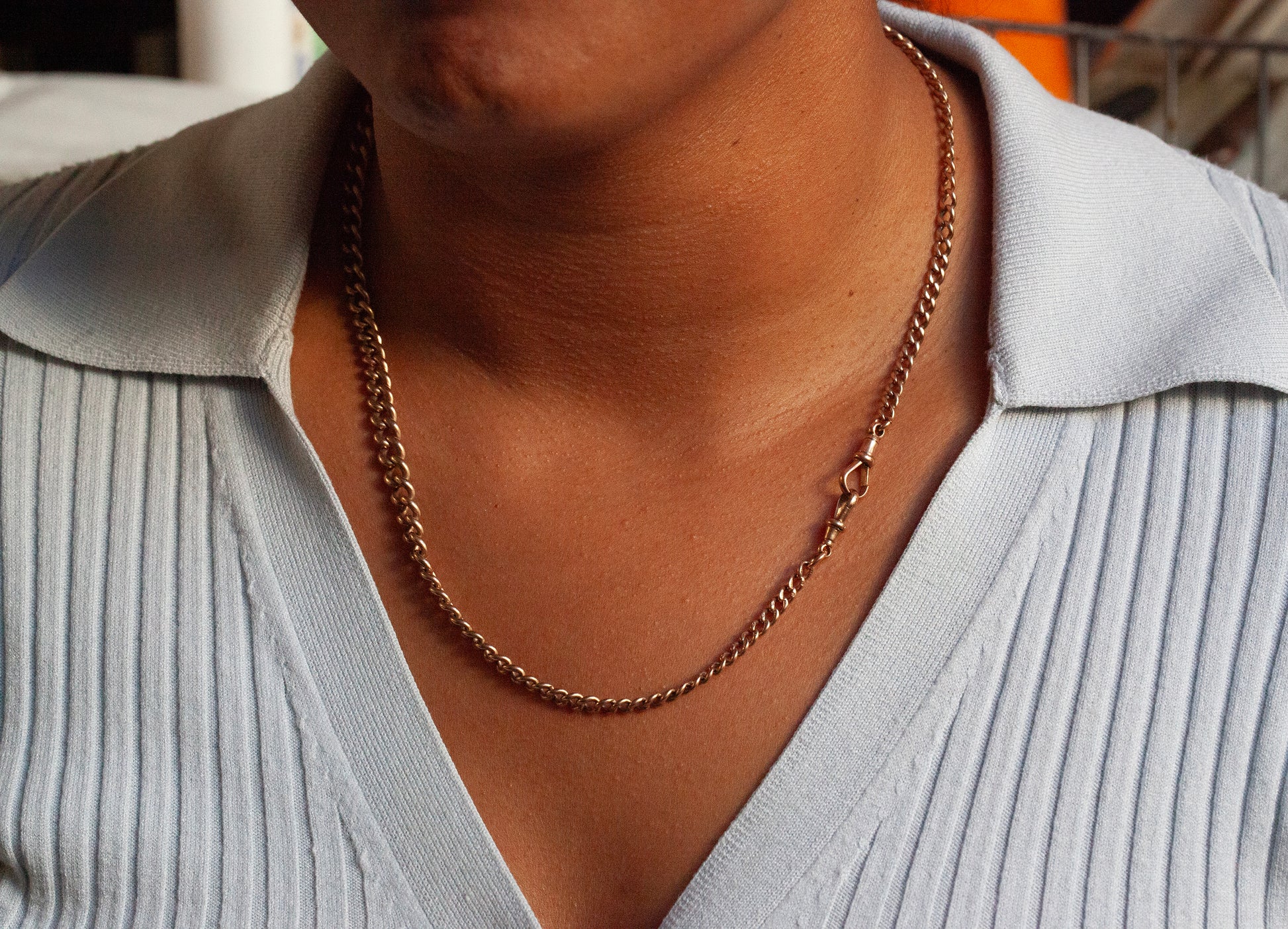 person wearing a gold albert chain with dog clasps 