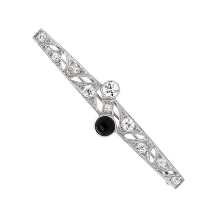 An Art Deco old cut diamond and onyx platinum brooch from the early 20th century.