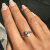 Hand wearing a ring with a clear stone on a dark background