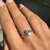 Hand wearing a ring with an opal stone on a blurred background