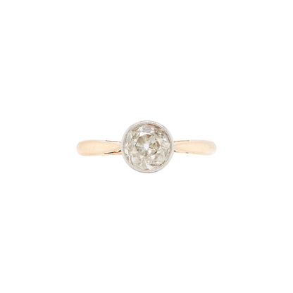 An Art Deco style solitaire diamond ring with a rub-over setting, featuring a millgrain edge on the band, photographed on a white background.