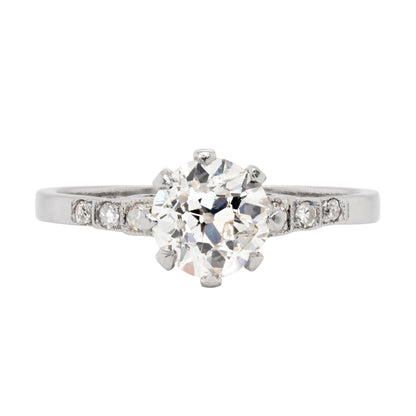 Antique engagement ring with a central old cut diamond and smaller diamonds on the sides, set in a platinum mounting with an open back design.