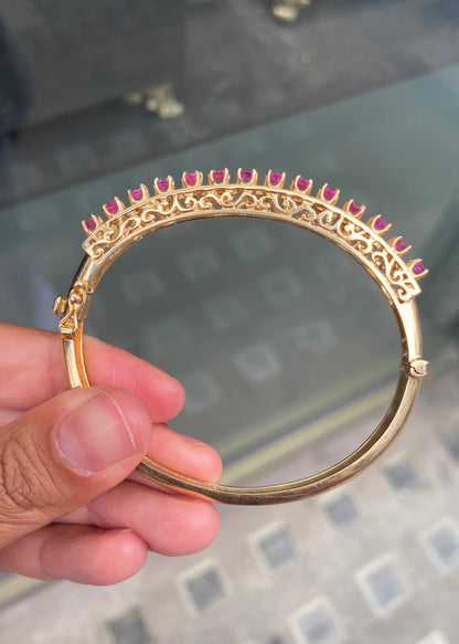 Vintage Ruby and 14 Carat Yellow Gold Open Work Hinged Bangle, circa 1980s