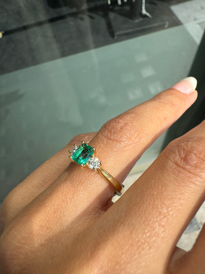 Gold ring with a green gemstone on a finger against a blurred background