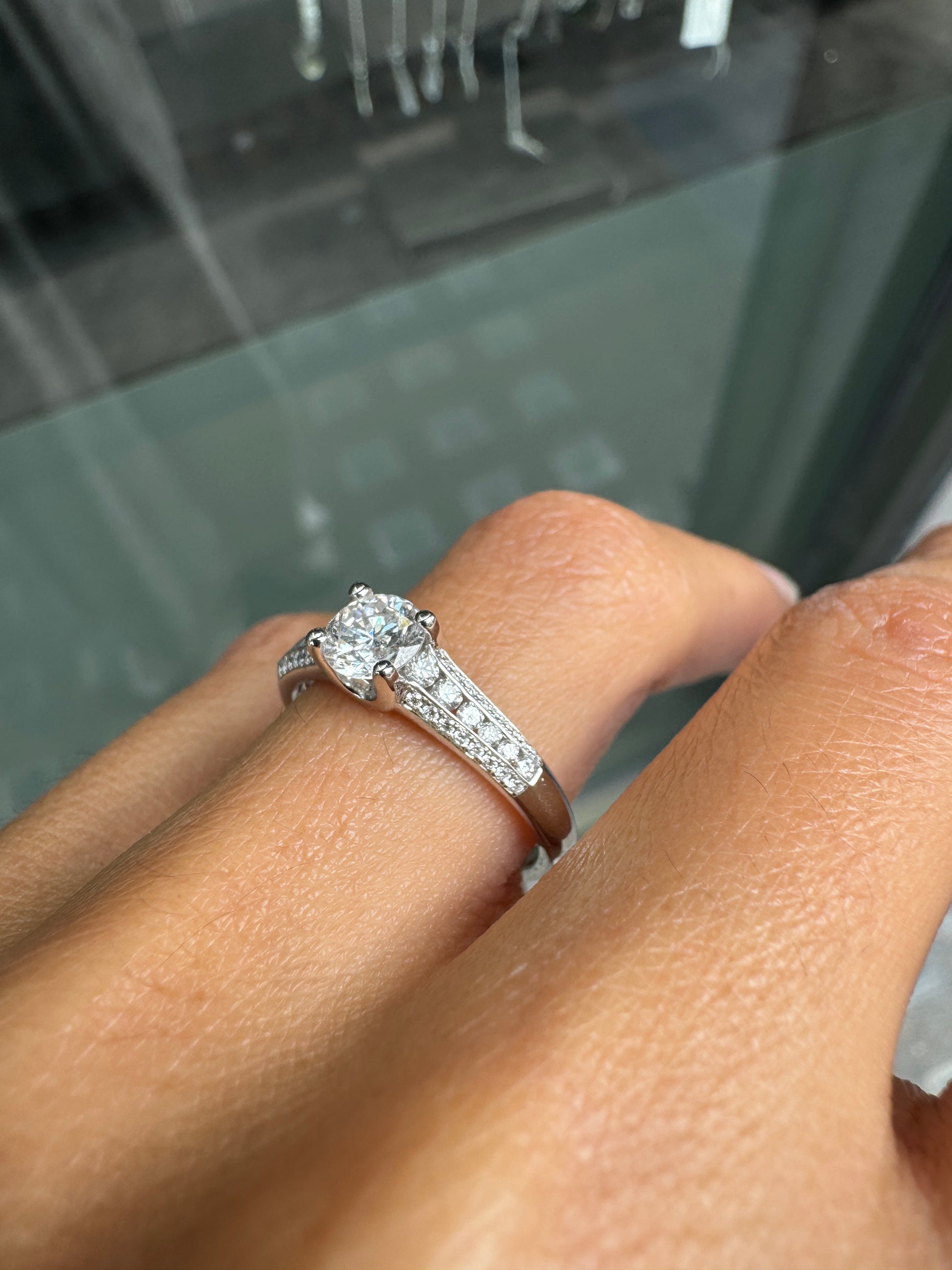 Close-up of a hand wearing a diamond ring with a blurred background