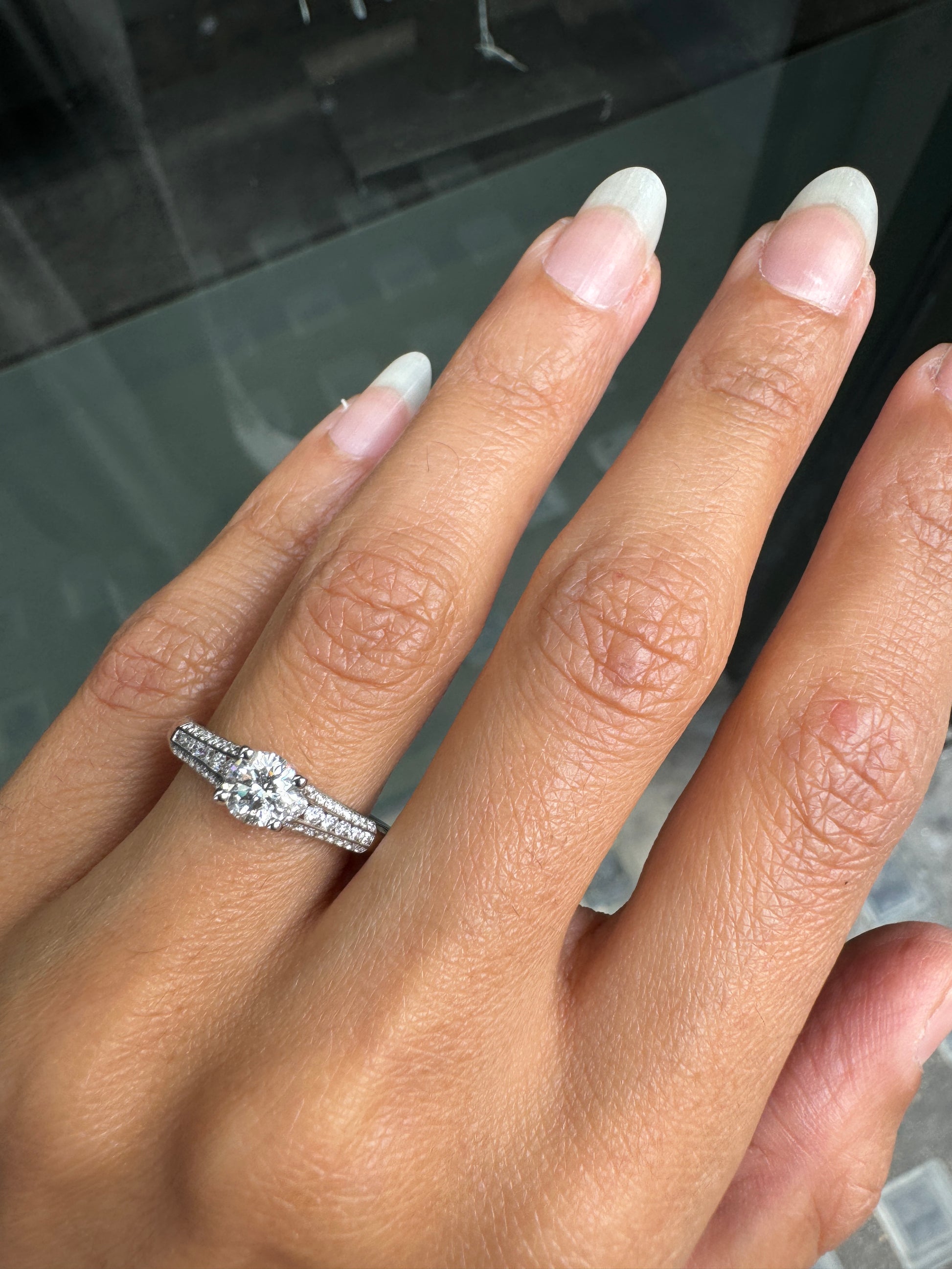 Close-up of a hand wearing a diamond ring with a blurred background