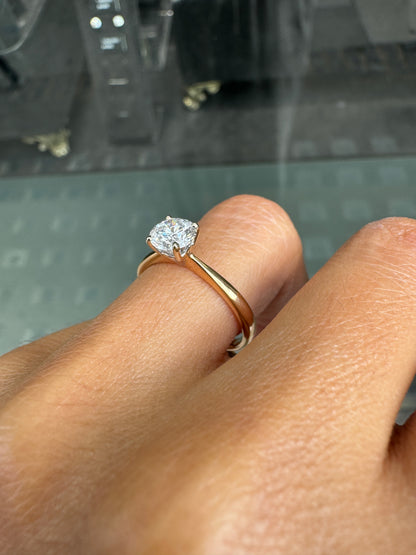 Close-up of a hand wearing a gold ring with a diamond on a blurred background