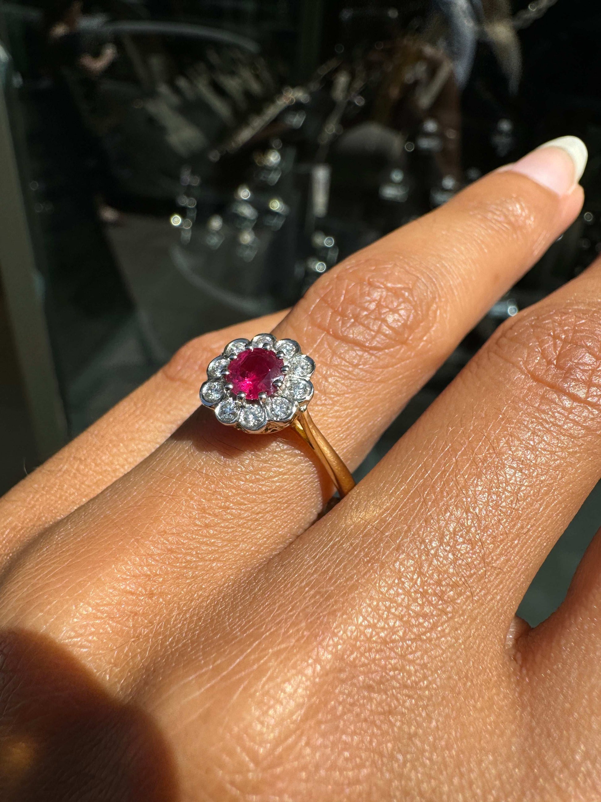 Close-up of a hand wearing a antique ruby ring with a red gemstone on a blurred background