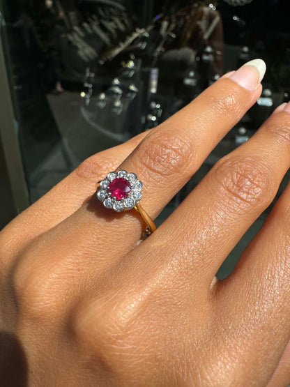 Close-up of a hand wearing a antique ruby ring with a red gemstone and diamond accents.