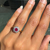 Hand wearing a ring with a red ruby gemstone, diamonds and a fine gold band