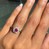Close-up of a hand wearing a ring with a red ruby gemstone and diamonds