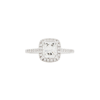 A cushion-cut diamond halo ring with white gold band, surrounded by round brilliant cut diamonds.