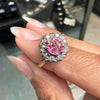 Pink sapphire ring with gold setting on a hand, blurred jewelry store background