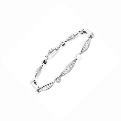 A vintage French pearl and diamond platinum bracelet with a series of alternating old cut diamonds and natural pearls, featuring a rub-over setting.