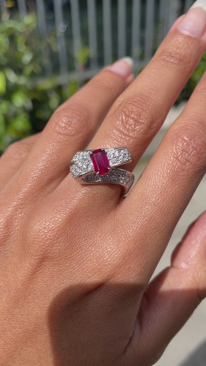 18ct white gold twisted ribbon dress ring with 1.04ct emerald cut ruby centre and 1.30ct round brilliant cut diamonds inlaid in two rows on hand