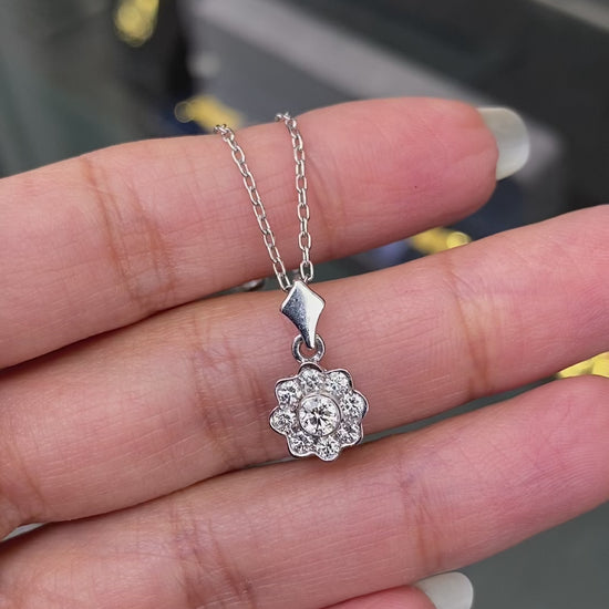 0.45 carat diamond flower cluster pendant crafted in 18 carat white gold, round brilliant cut diamonds arranged in a floral design, suspended from a delicate white gold chain. on hand