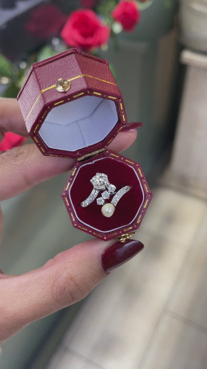 An antique engagement ring featuring a central diamond, flanked by two smaller diamonds and a pearl, all set in platinum on a rose gold mount in box