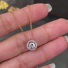 An 18 carat rose gold halo cluster pendant featuring a round brilliant cut diamond center stone with a halo of smaller round diamonds, suspended on a slender gold chain. on hand