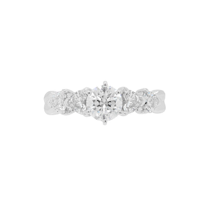A round brilliant cut diamond engagement ring with two heart shaped diamonds on either side, set in a six claw open back setting in platinum.